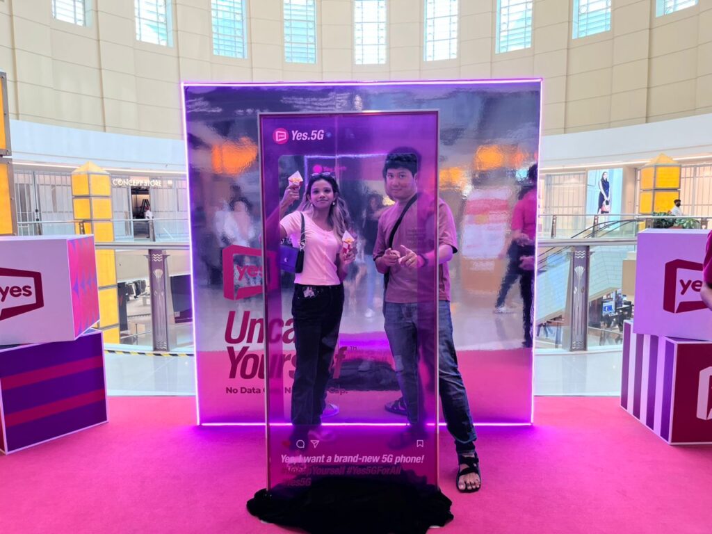 Two people standing in front of a backdrop with Yes 5G graphics.